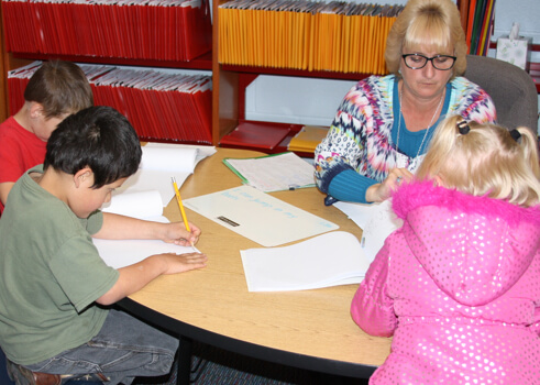 A female teacher working with students at a desk