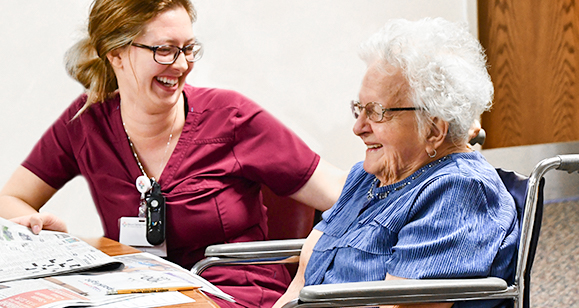 nurse smiling with older patient in wheelchair