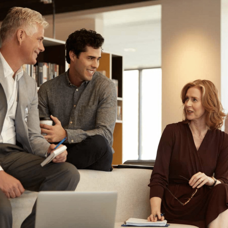 Three people are talking on a sofa