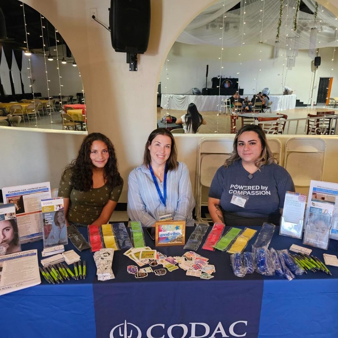 3 employees sitting at the Codac Health System's booth in a fair