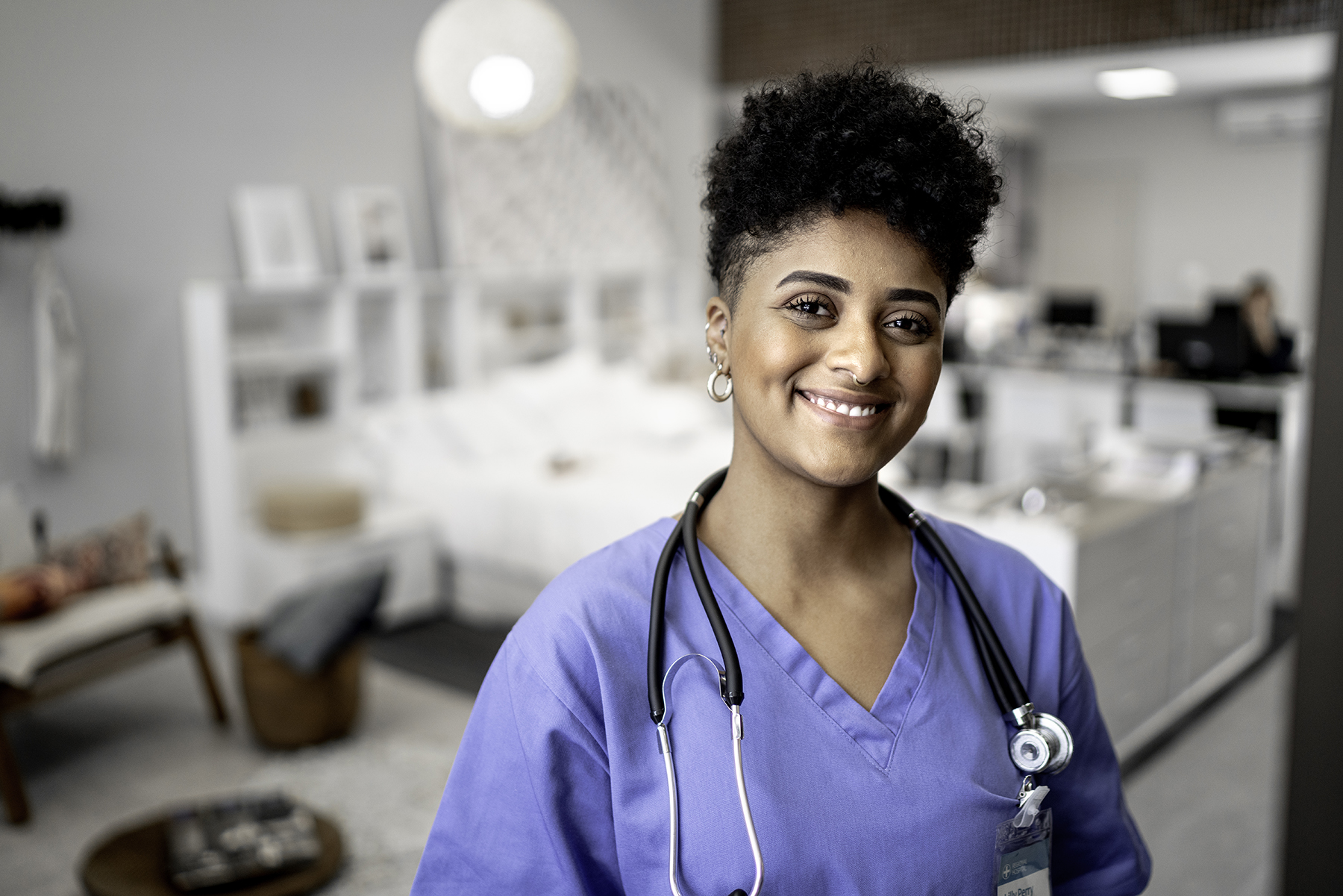 A woman in medical scrubs stands at a counter, engaged in her work environment, showcasing professionalism and care.