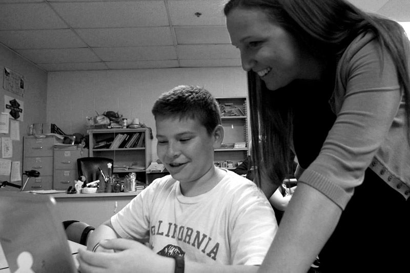 teacher looking over student's work on a computer